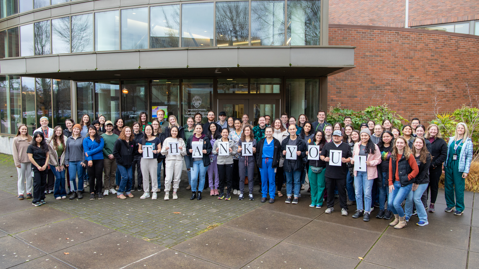The veterinary class of 2025 poses in front of Magruder Hall for a group photo with signs spelling out T H A N K Y O U