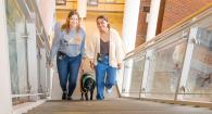 Emmie and Erin walk with Newton up stairs in the college atrium