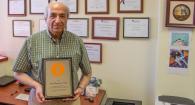 Dr. Hadi Mansouri poses in his office with his Zoetis Distinguished Veterinary Teacher Award