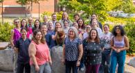 Group photo of OVDL staff surrounding a bronze beaver statue in front of Magruder Hall
