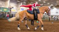 Girl balances on Toby, a Belgian draft horse, during an equine vaulting competition