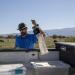 Man holds mosquito trap in pasture.
