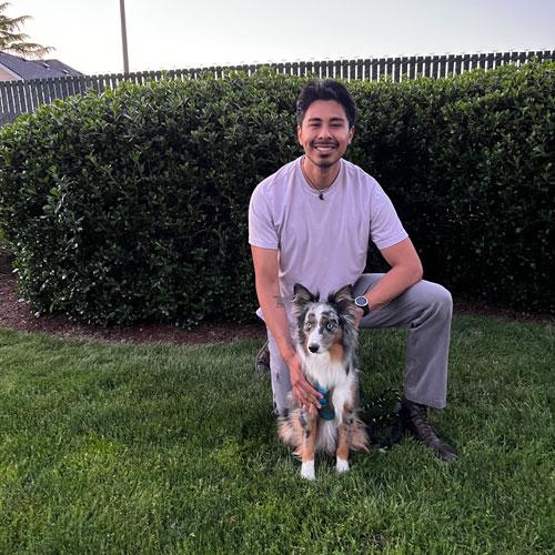 Luis and dog pose on a lawn