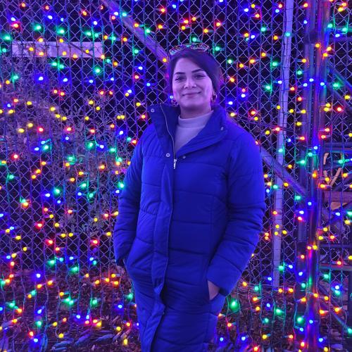 Simran Nagi standing outside in front of winter lights
